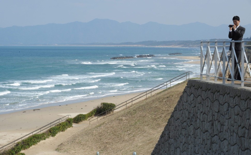 epa02085485 A Japanese man photographs the Japan Sea at a beach near Yanago city, Tottori province, Japan 19 March 2010. Depopulation is a growing problem in Tottori, the least populated province in Japan.  EPA/EVERETT KENNEDY BROWN