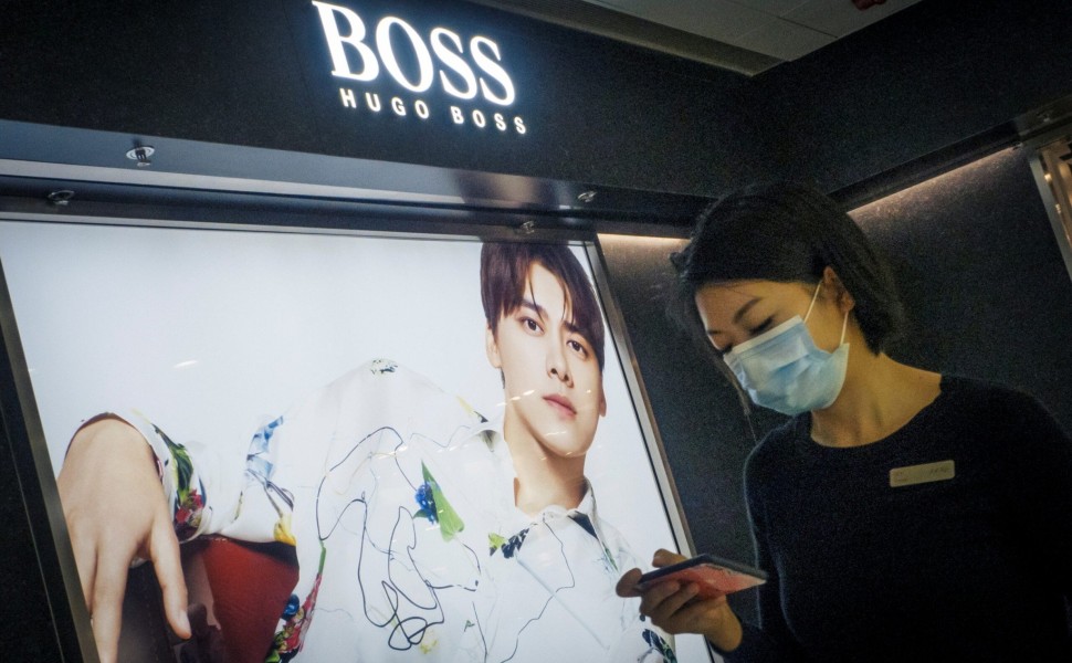 A woman walks past a store of German fashion house Hugo Boss in Beijing, China, March 27, 2021. REUTERS/Thomas Peter A woman walks past a store of German fashion house Hugo Boss in Beijing, China, March 27, 2021. REUTERS/Thomas Peter