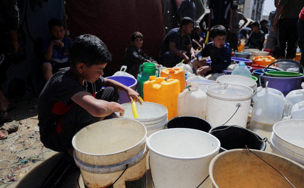 Palestinian children fill water containers at a tent camp, in Gaza - Reuters