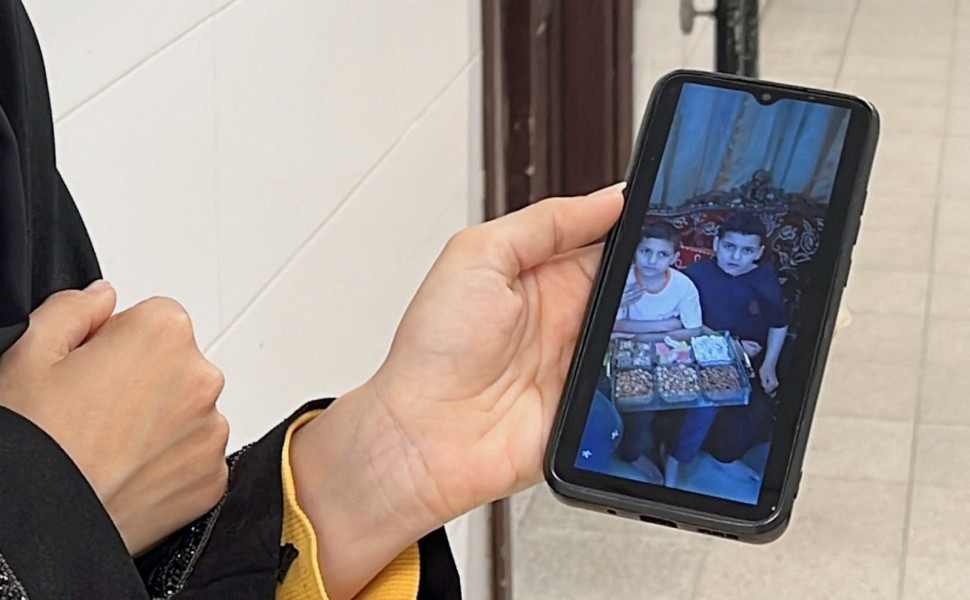 Η χαροκαμένη μάνα, δείχνει από το κινητό της τα δύο από τα δέκα παιδιά της/Φωτ. REUTERS